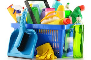 Shopping basket with detergent bottles and chemical cleaning supplies isolated on white