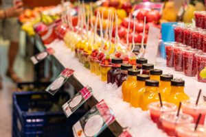 Juices and fresh packaged fruit, on the shelf of a greengrocer